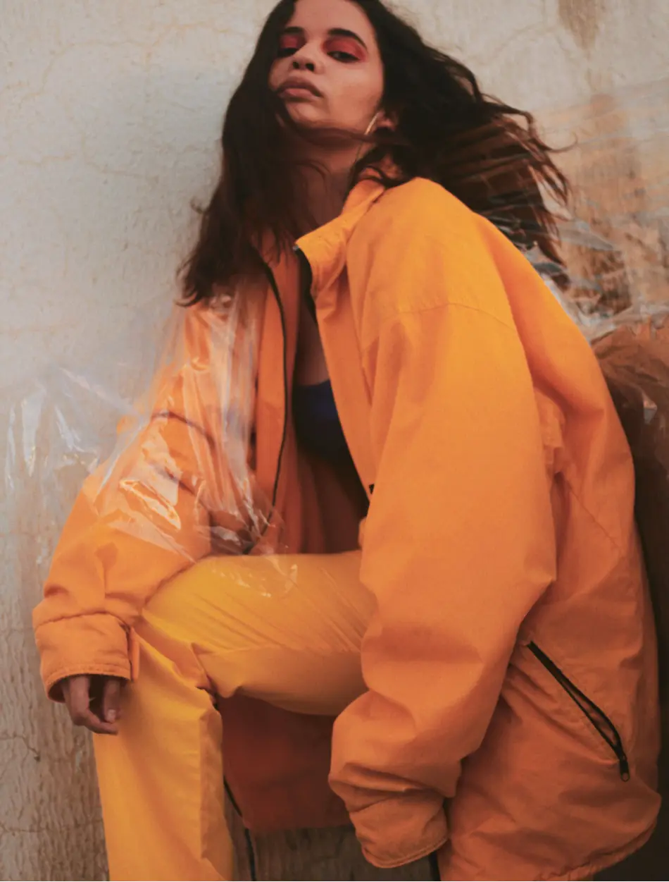Editorial picture of a woman in orange sport wear, looking down